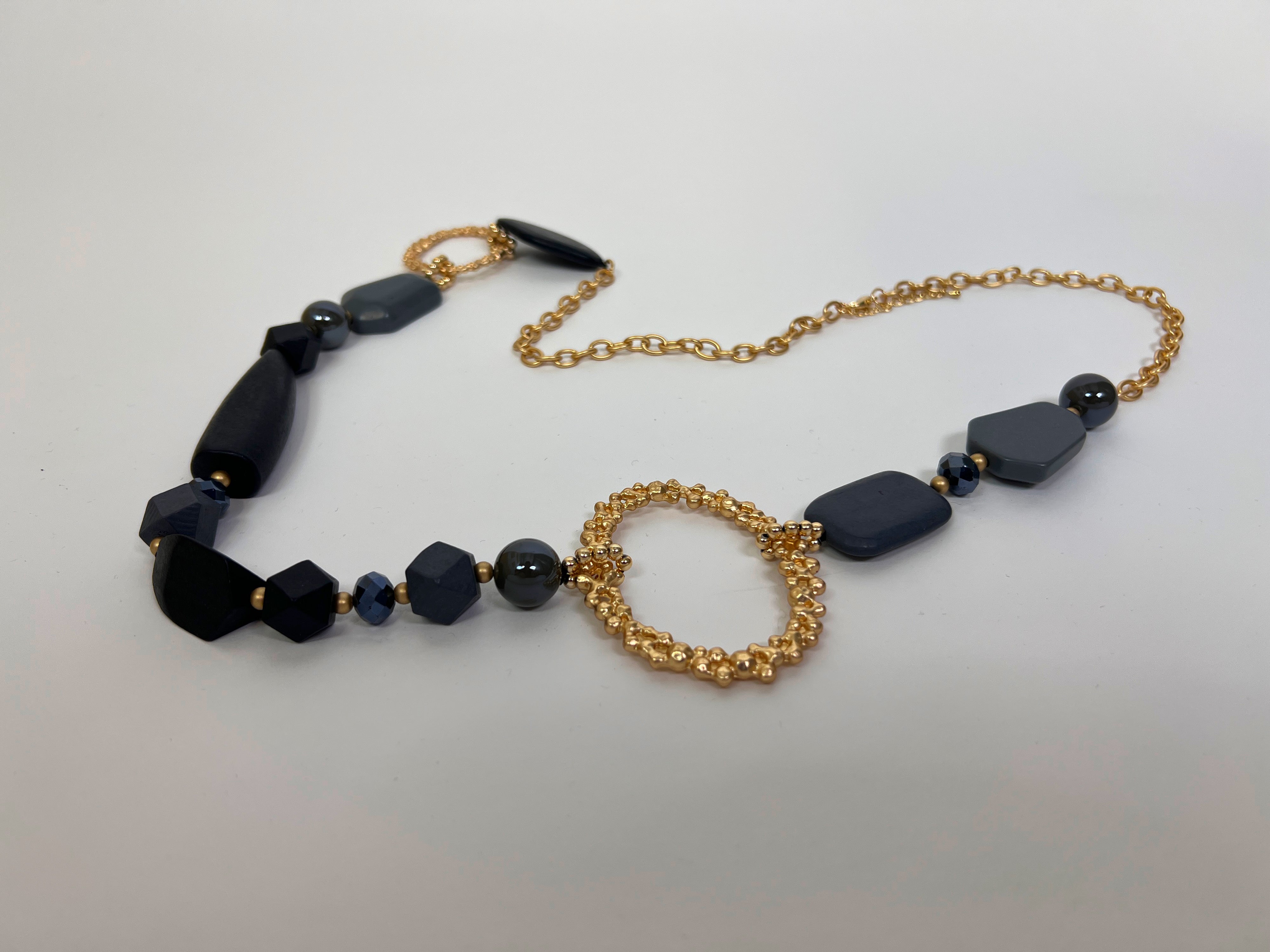 Necklace with black beads and gold chain on a white background